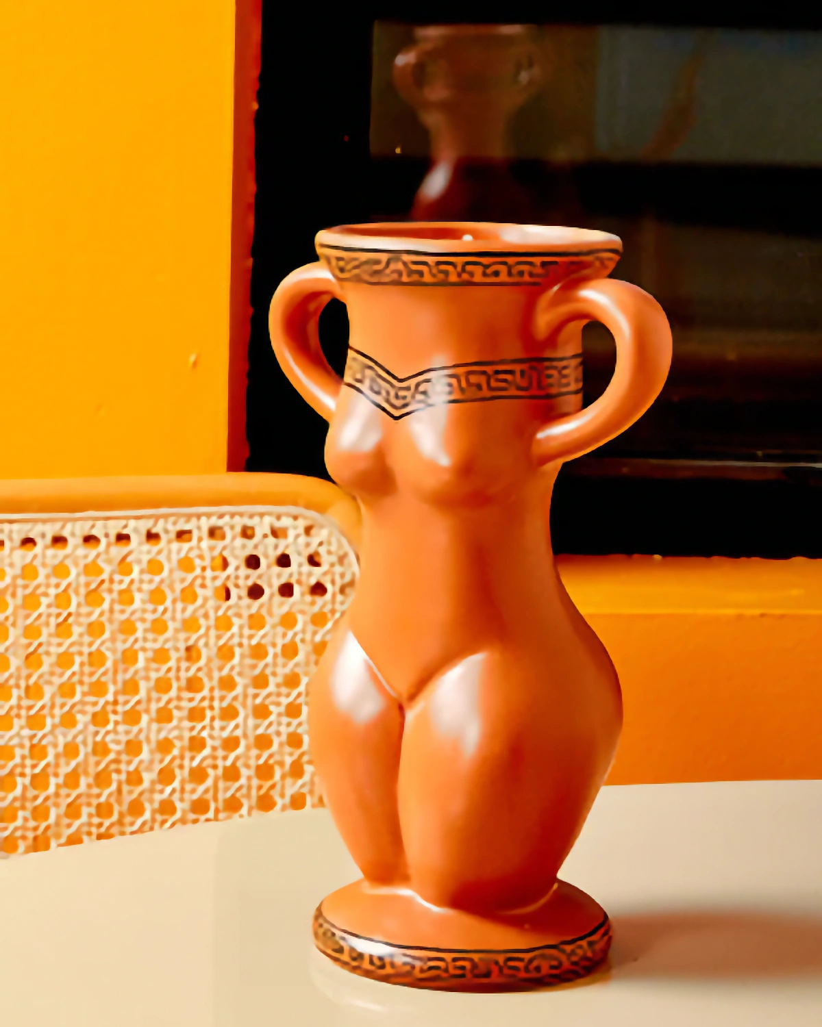 Orange ceramic vase against a marigold backdrop