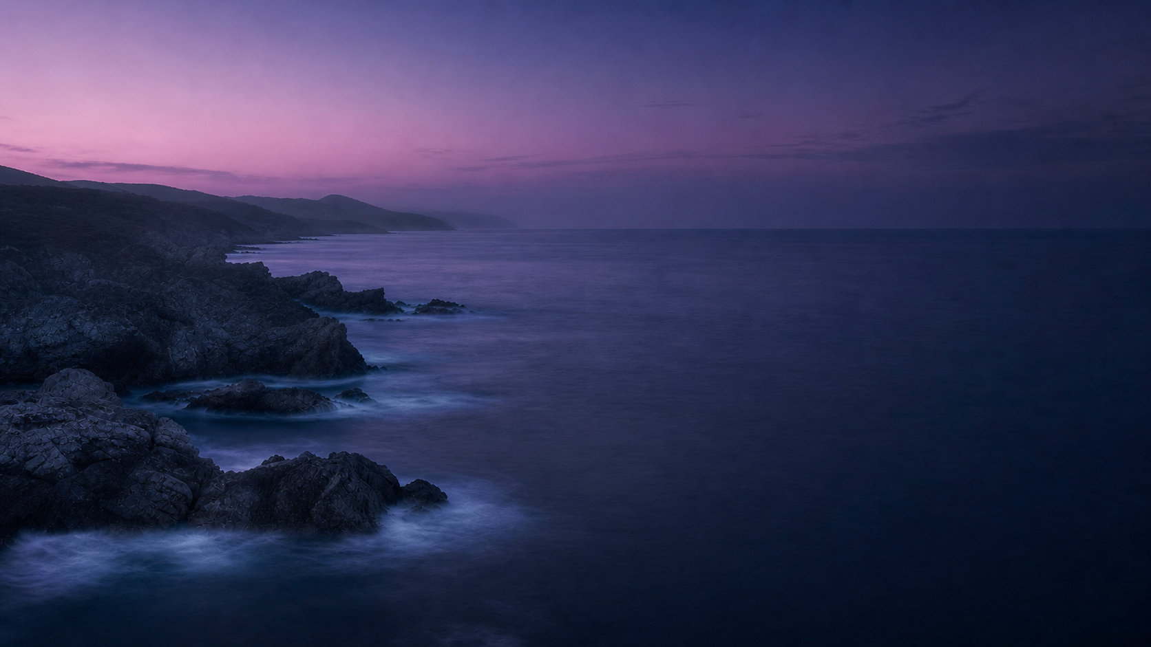 Rocky coastline and calm ocean at lavender blue hour