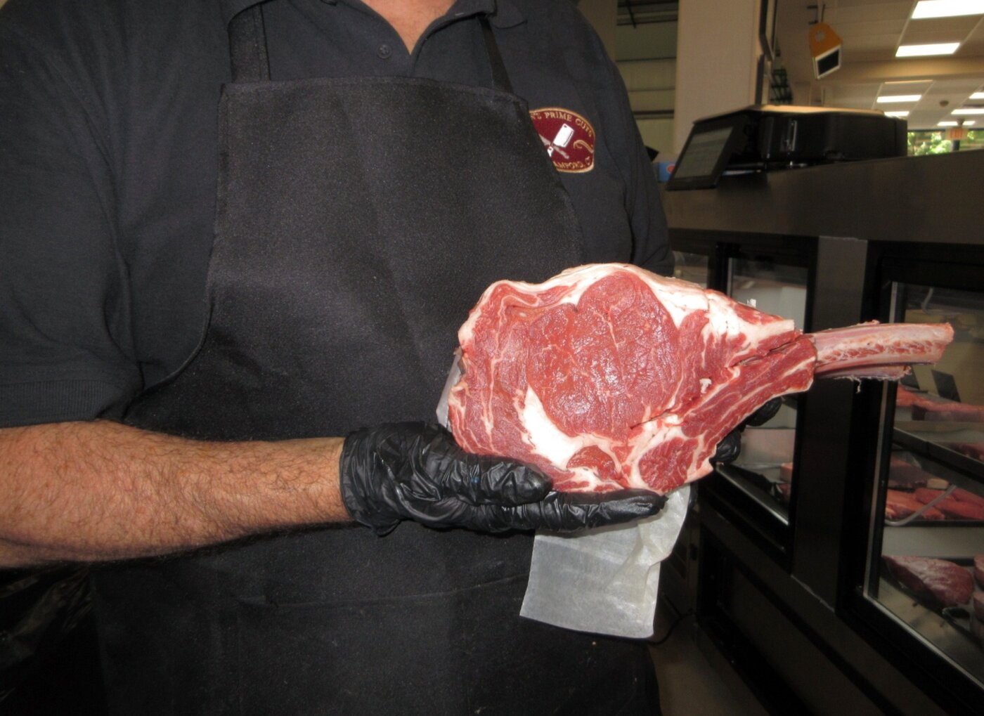 Chris Deenihan holding a bone-in tomahawk ribeye at Deenihan's Prime Cuts.