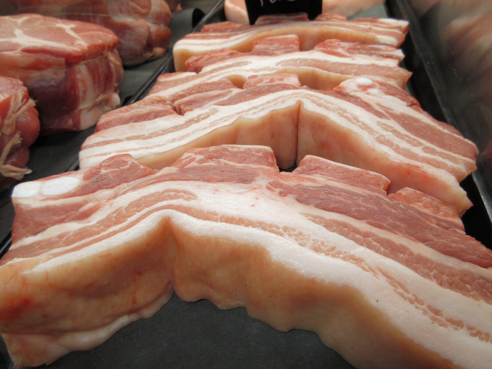 Fresh sliced pork belly in the display case at Deenihan's Prime Cuts.