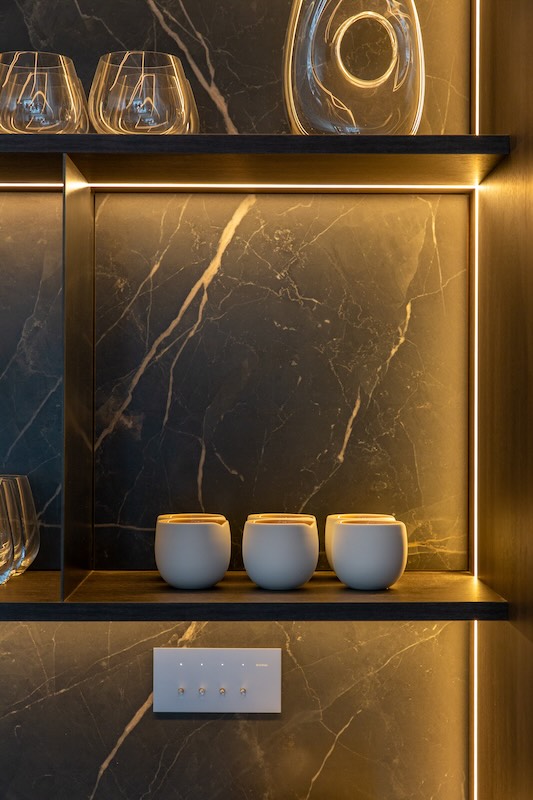 Luxury kitchen with under-cabinet LED lighting and dark marble feature wall