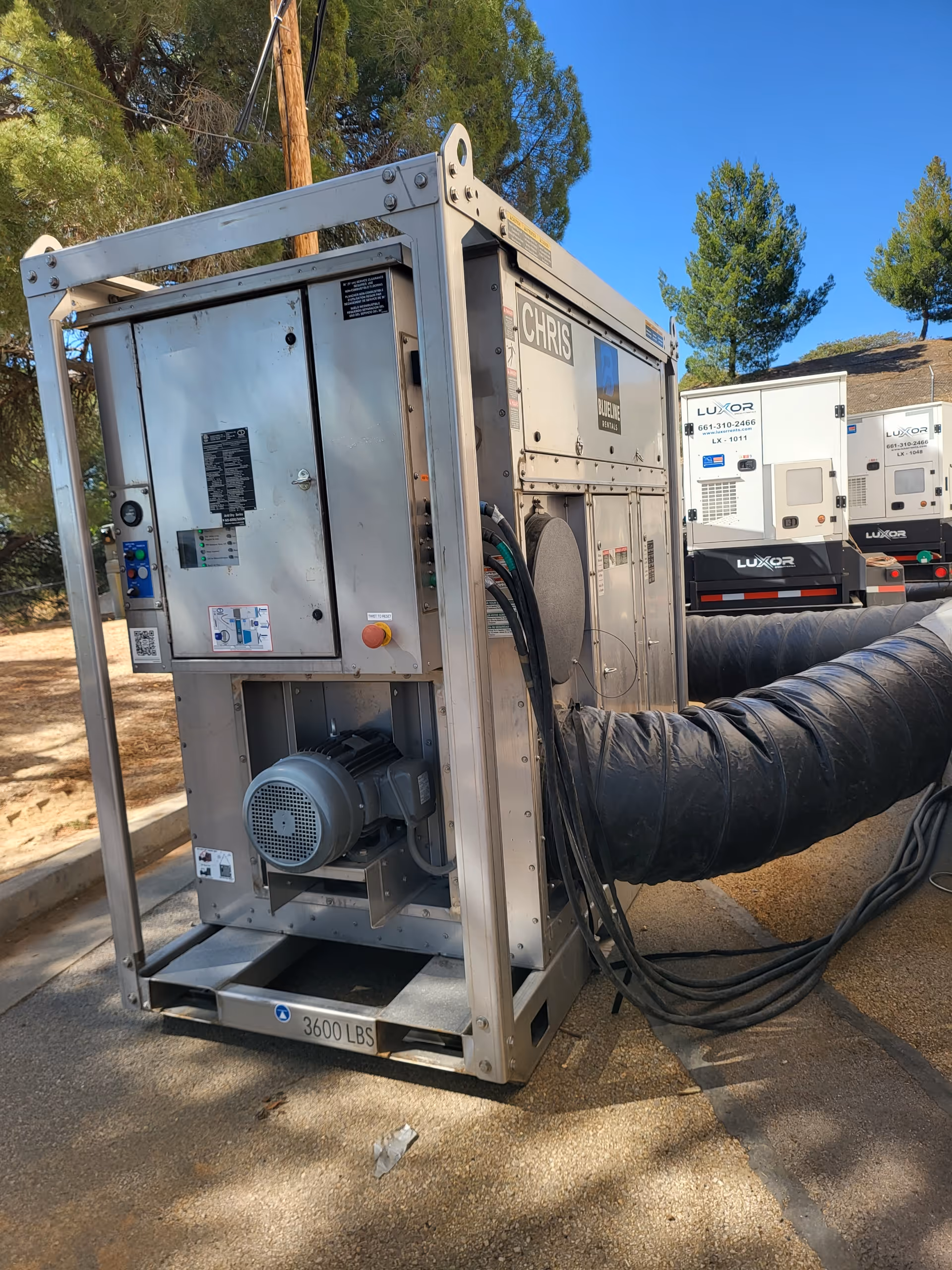 Large metal industrial machine with hoses, labeled 'CHRIS' and weighs 3600 lbs outdoors.