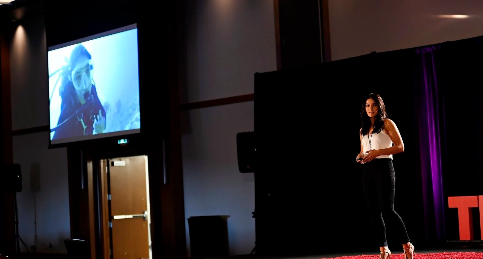 Emily speaking on stage as a guest speaker at a TEDx Kanata event.