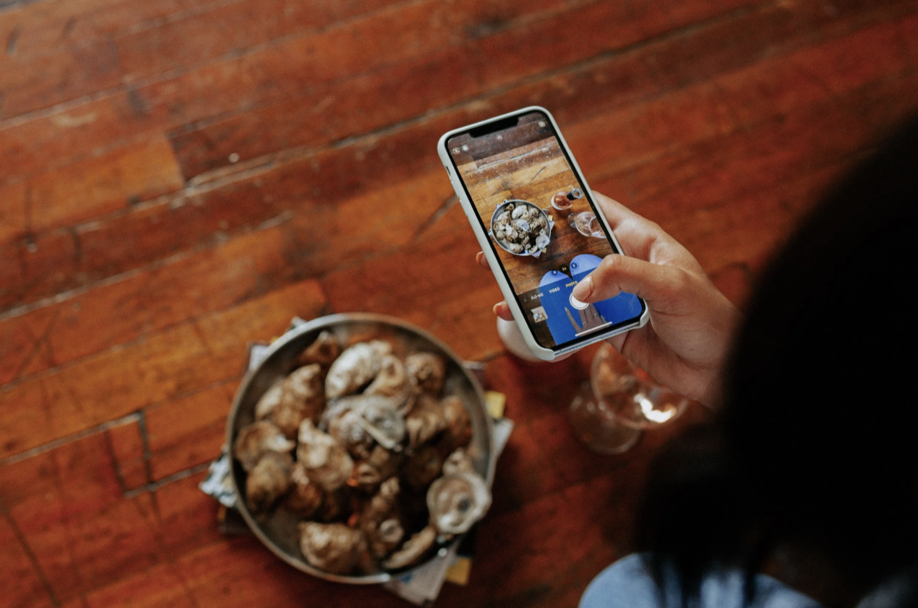 A person taking a photo of oysters in a bowl with their smart phone.