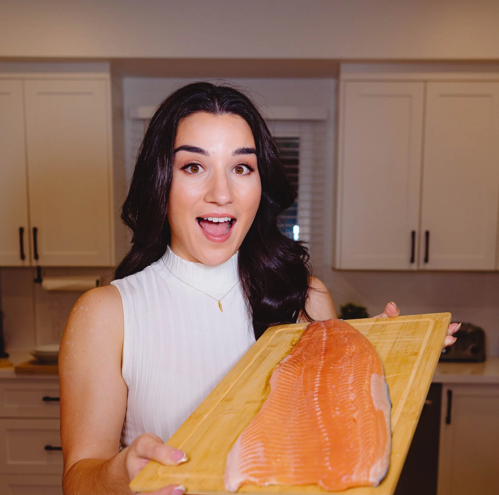 Emily holding a piece of salmon showing its natural pink colour.