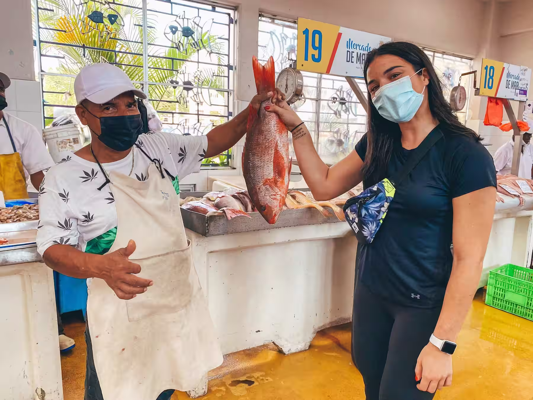 Emily holding a fresh fish with a fishermen at Panama City’s Mercado de Mariscos at the seafood market in Casco Viejo.