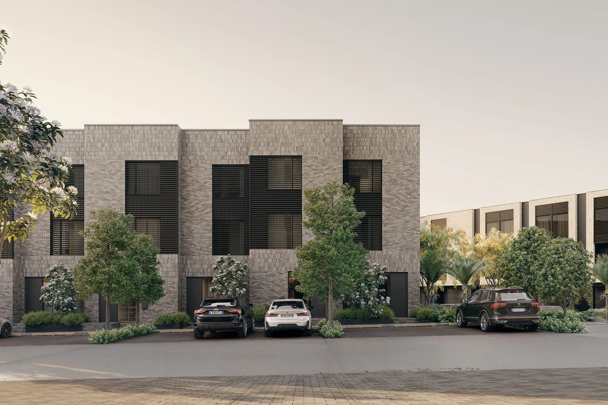 Textured grey brick facades of Enclave townhouses with black timber window screens