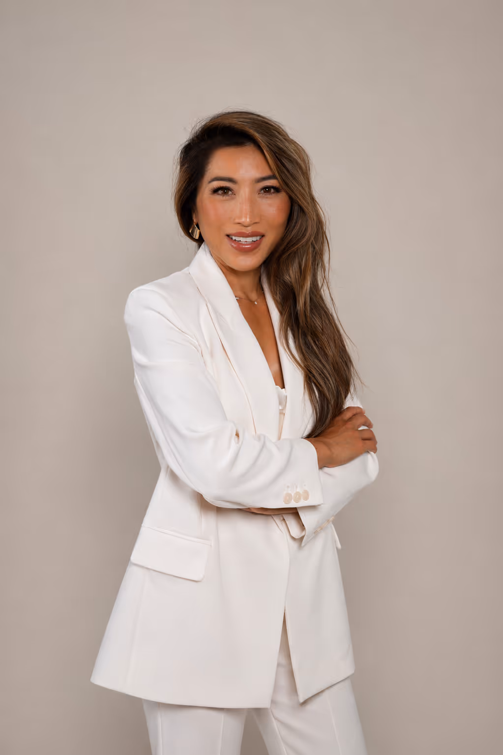Dr.Nency with long hair wearing white suit jacket and pants against a plain background.