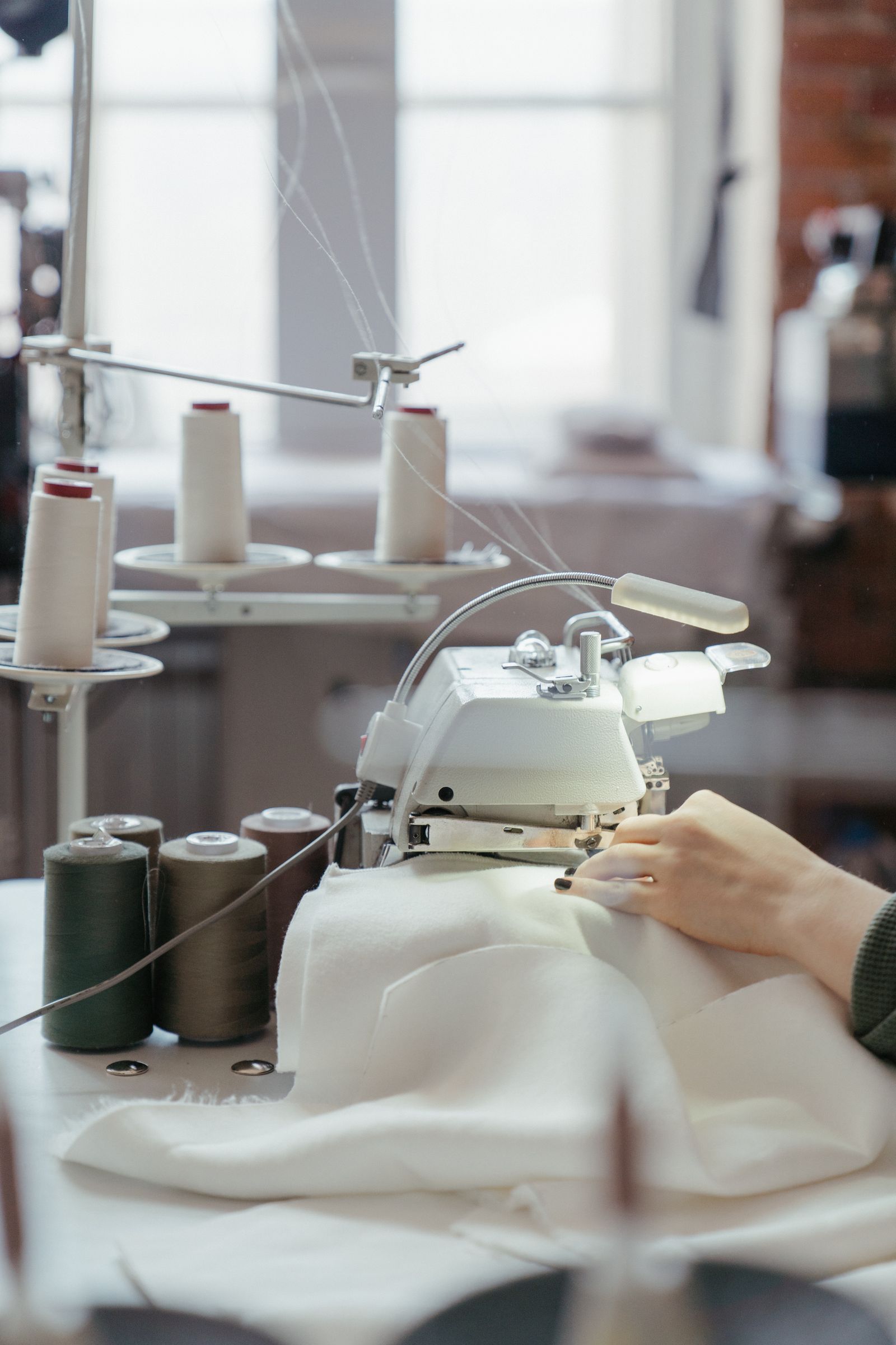 Handen aan een industriele overlock in het atelier van De Vlinder