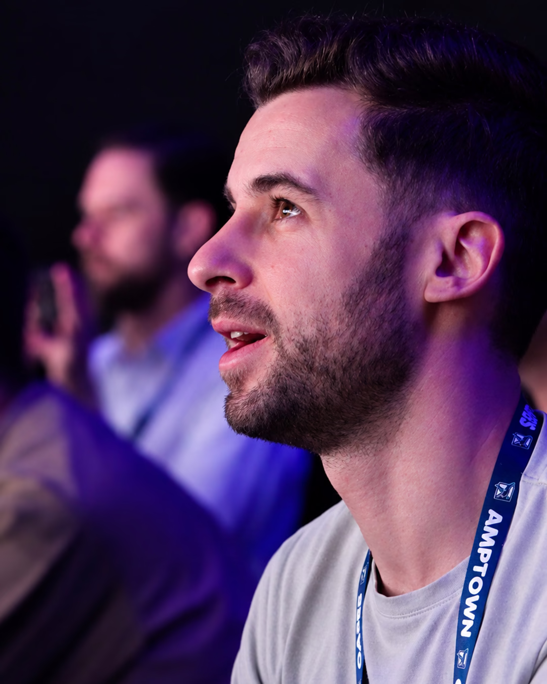 Audience member watching the presentation under purple stage lighting.