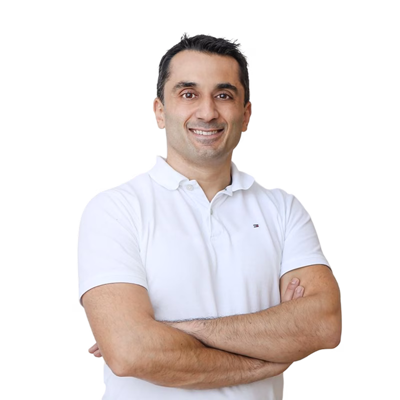 Smiling man in a white polo shirt with arms crossed.