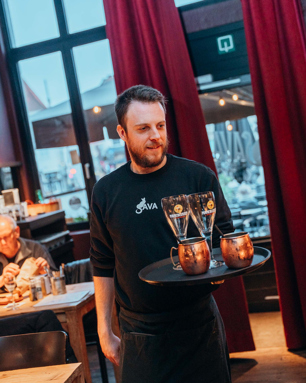 Kelner van Sava brengt Maneblusser-bieren en cocktails naar de tafel
