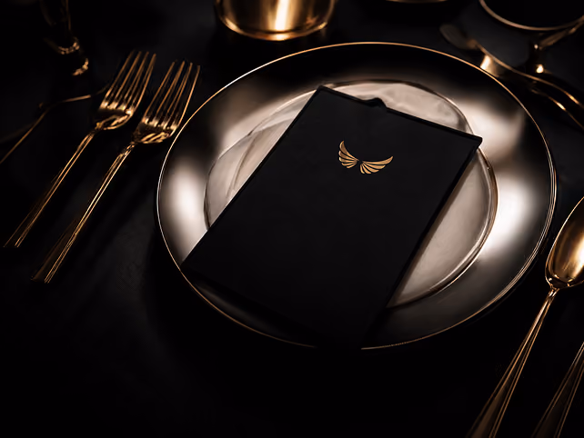 Elite Luxz Events branded menu card on a gold-rimmed place setting with polished flatware