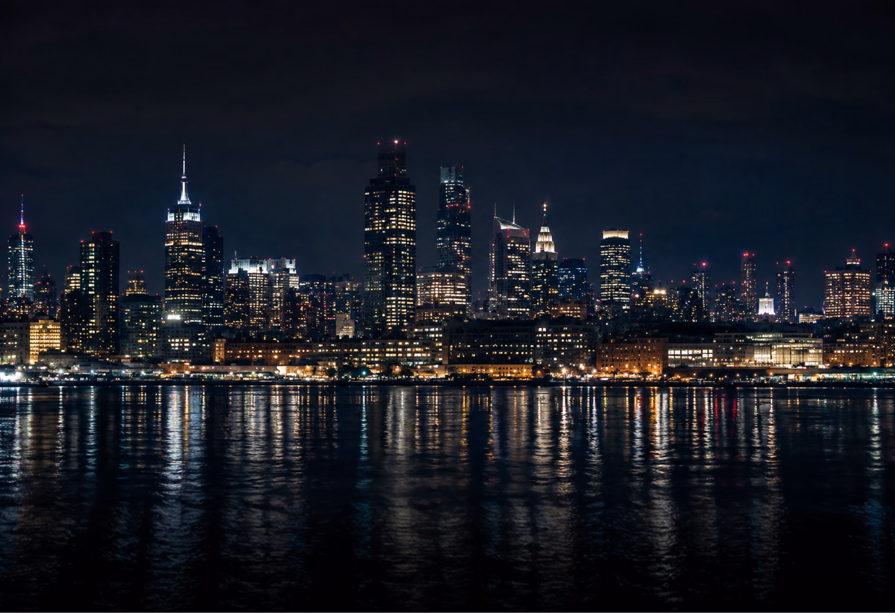 Nighttime city skyline reflected over the water
