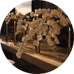 Decorative dried flowers in a glass vase on a wooden table with candles in the background.