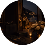 Dimly lit room with a flower vase and candles, overlooking a cityscape with lights at night.