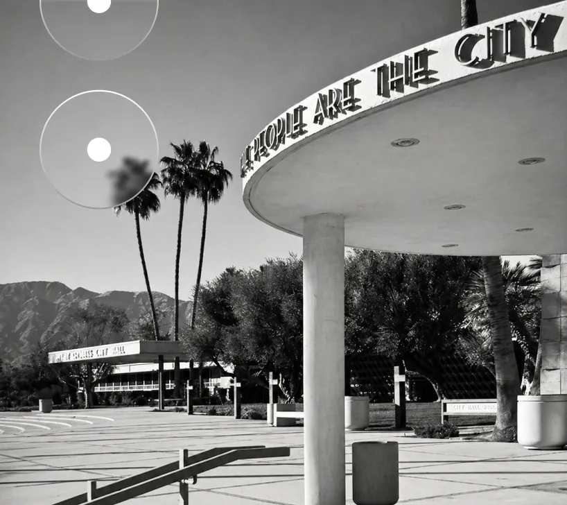 Black and white photo of a city hall entrance with palm trees and mountains in the background.