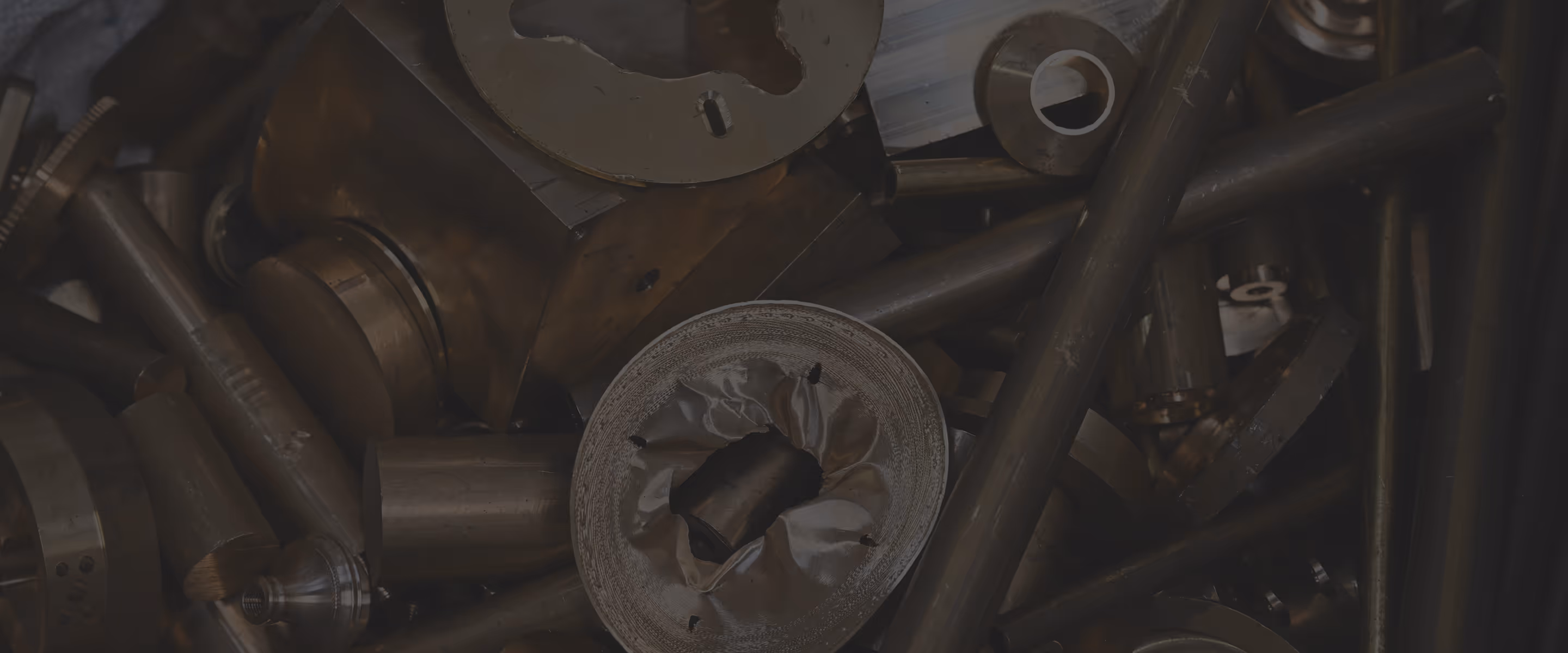 Close-up of various dark metal industrial parts and cylindrical components piled together.