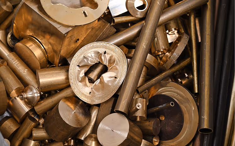 Various brass metal rods, cylinders, and components piled together.