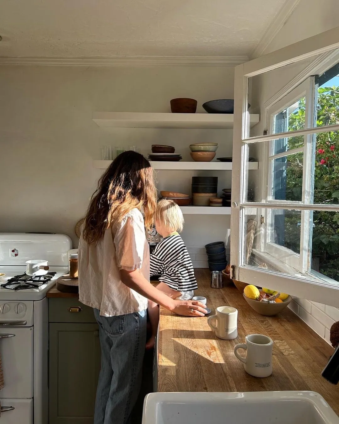 Two people unpacking in a bright kitchen beside a window