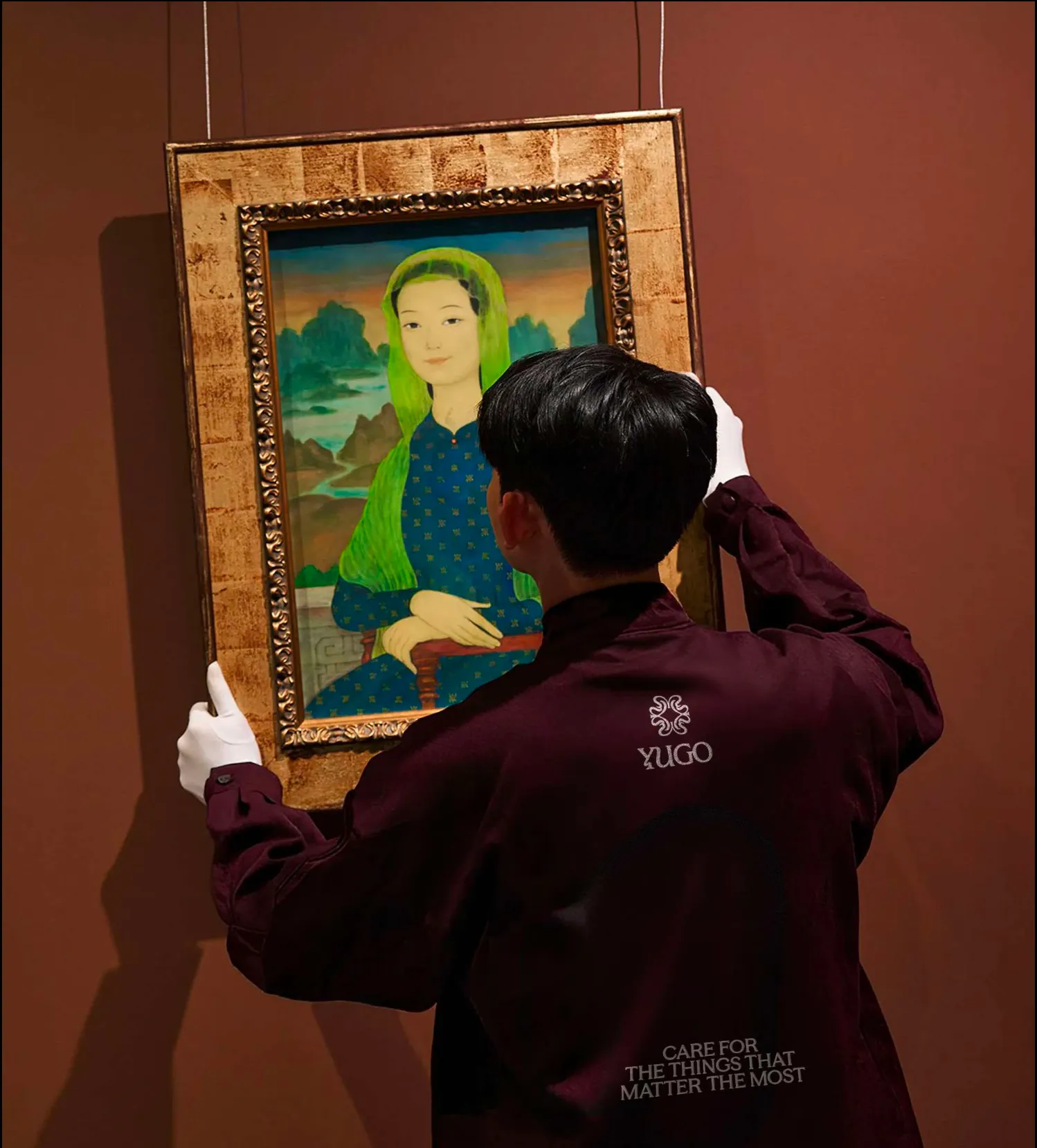A Yugo crew member in white gloves hanging a framed painting