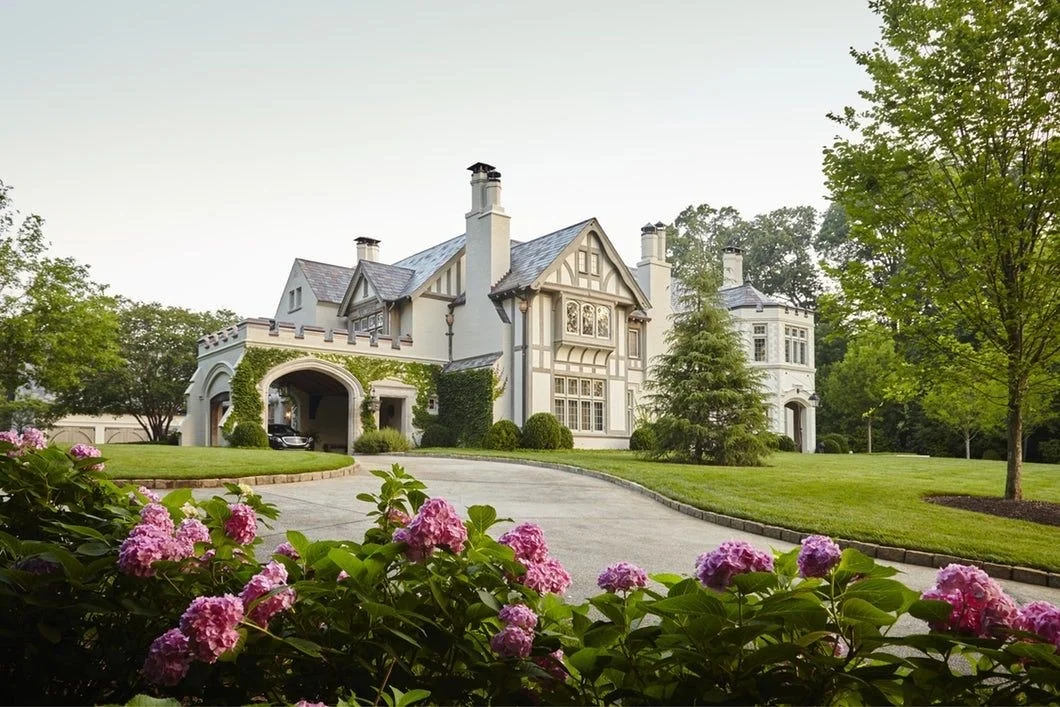 A Tudor-style estate behind a lawn and blooming pink hydrangeas