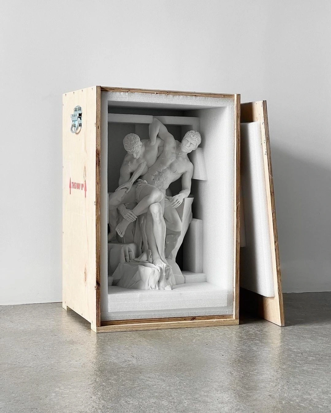 A marble sculpture held in an open wooden crate