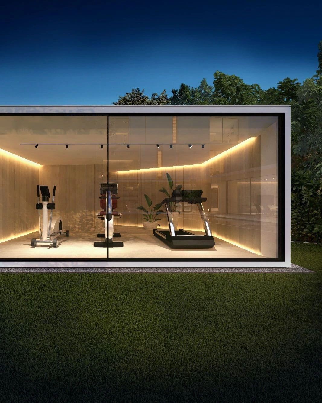 A glass-walled home gym lit warmly at dusk with exercise equipment inside