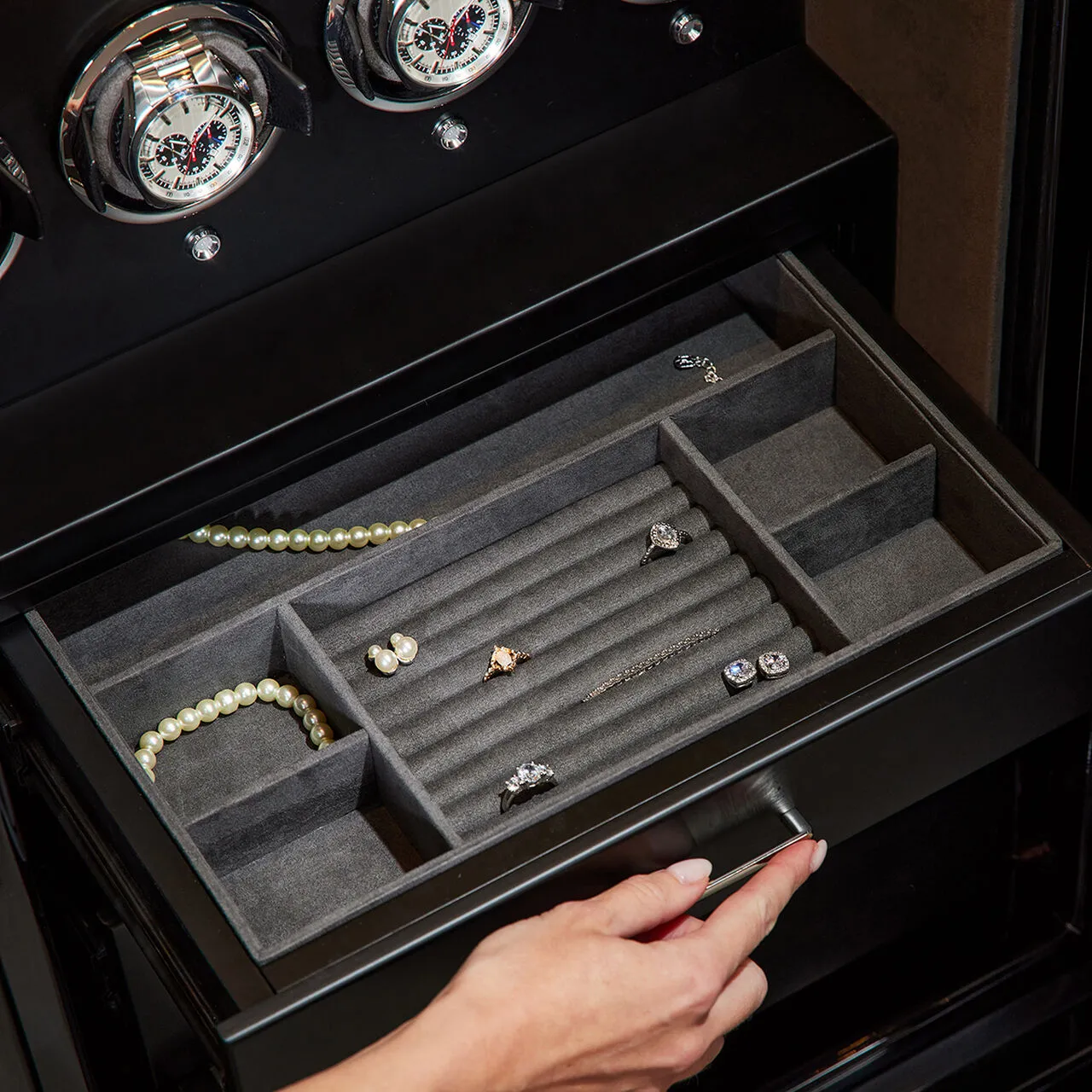 A hand opening a velvet jewellery drawer inside a watch winder safe
