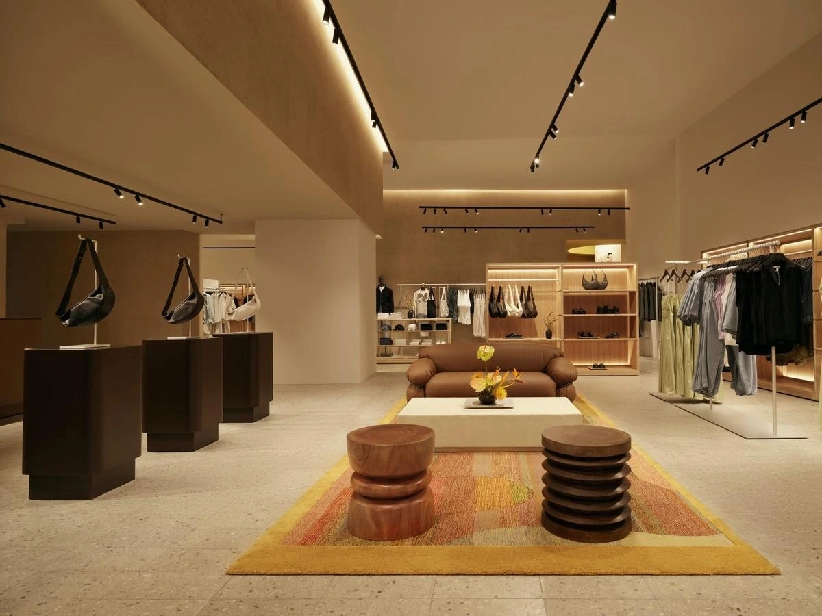 A minimal retail store with clothing rails and sculptural stools