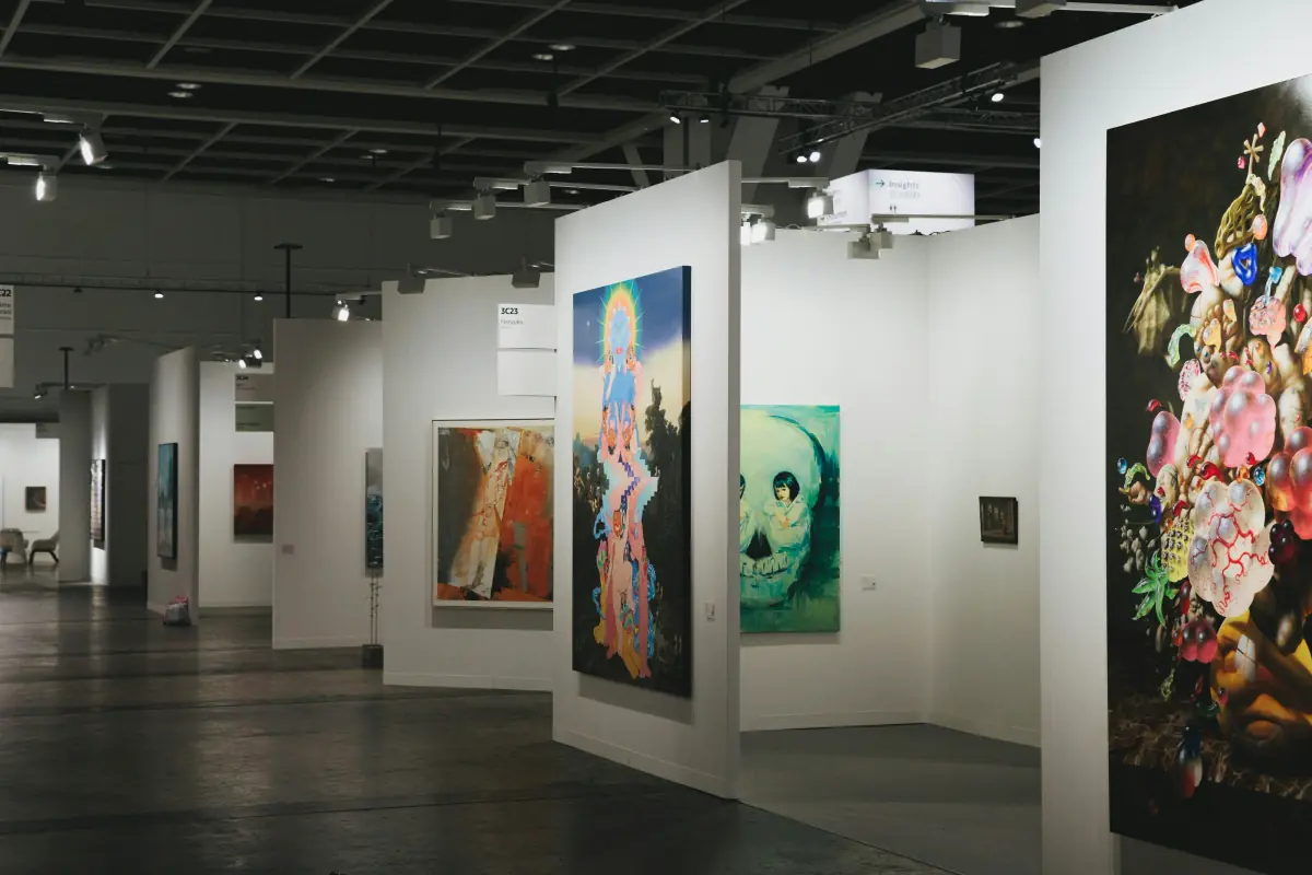 A long art fair aisle lined with white walls and large colourful paintings