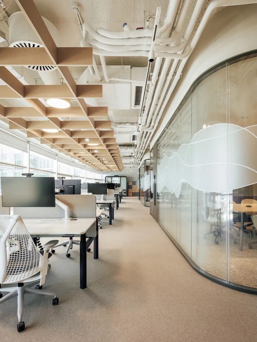 A modern office floor with a curved glass meeting room and timber ceiling