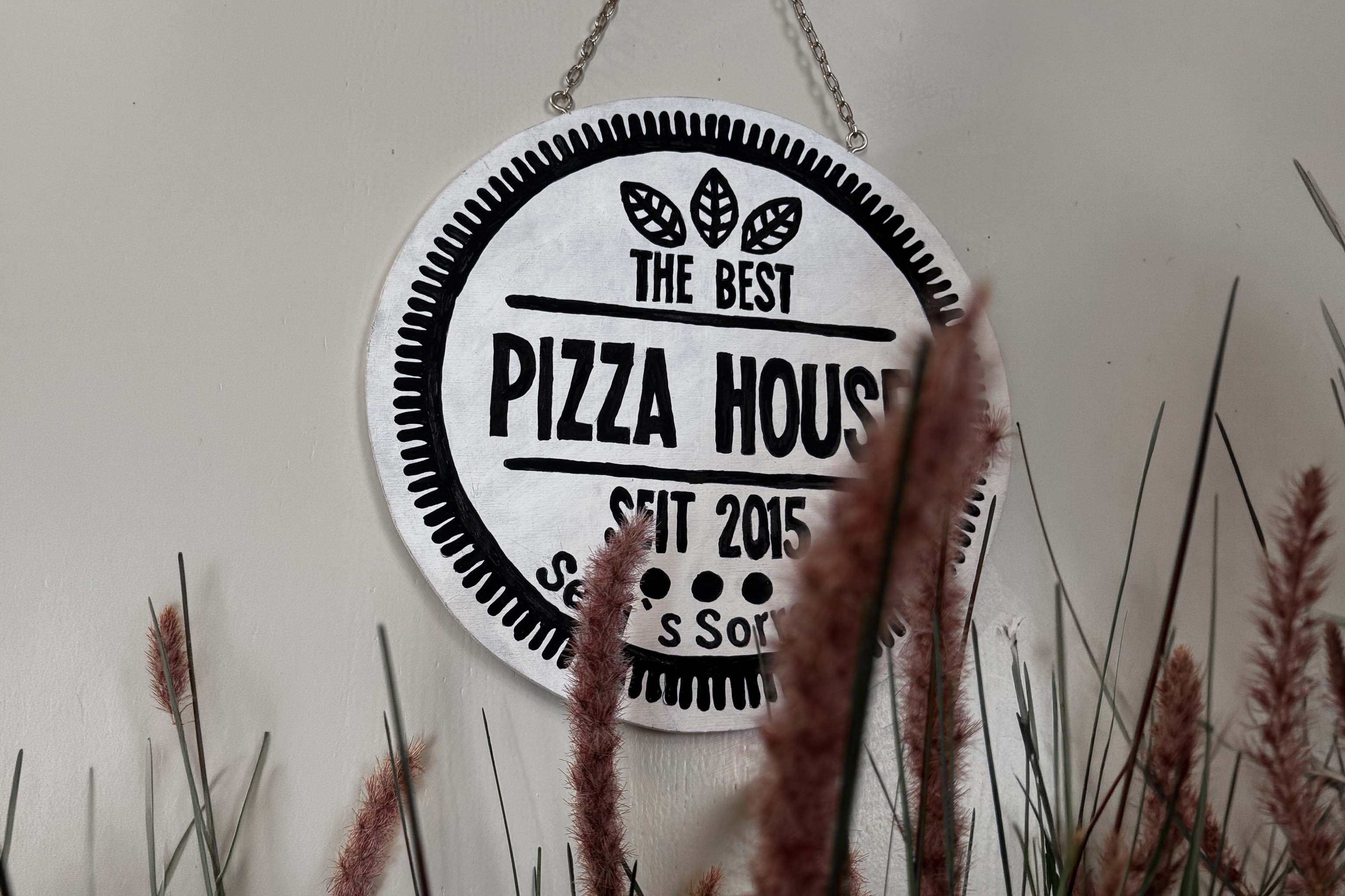 Rundes Schild an einer Wand mit der Aufschrift: The Best Pizza House seit 2015.