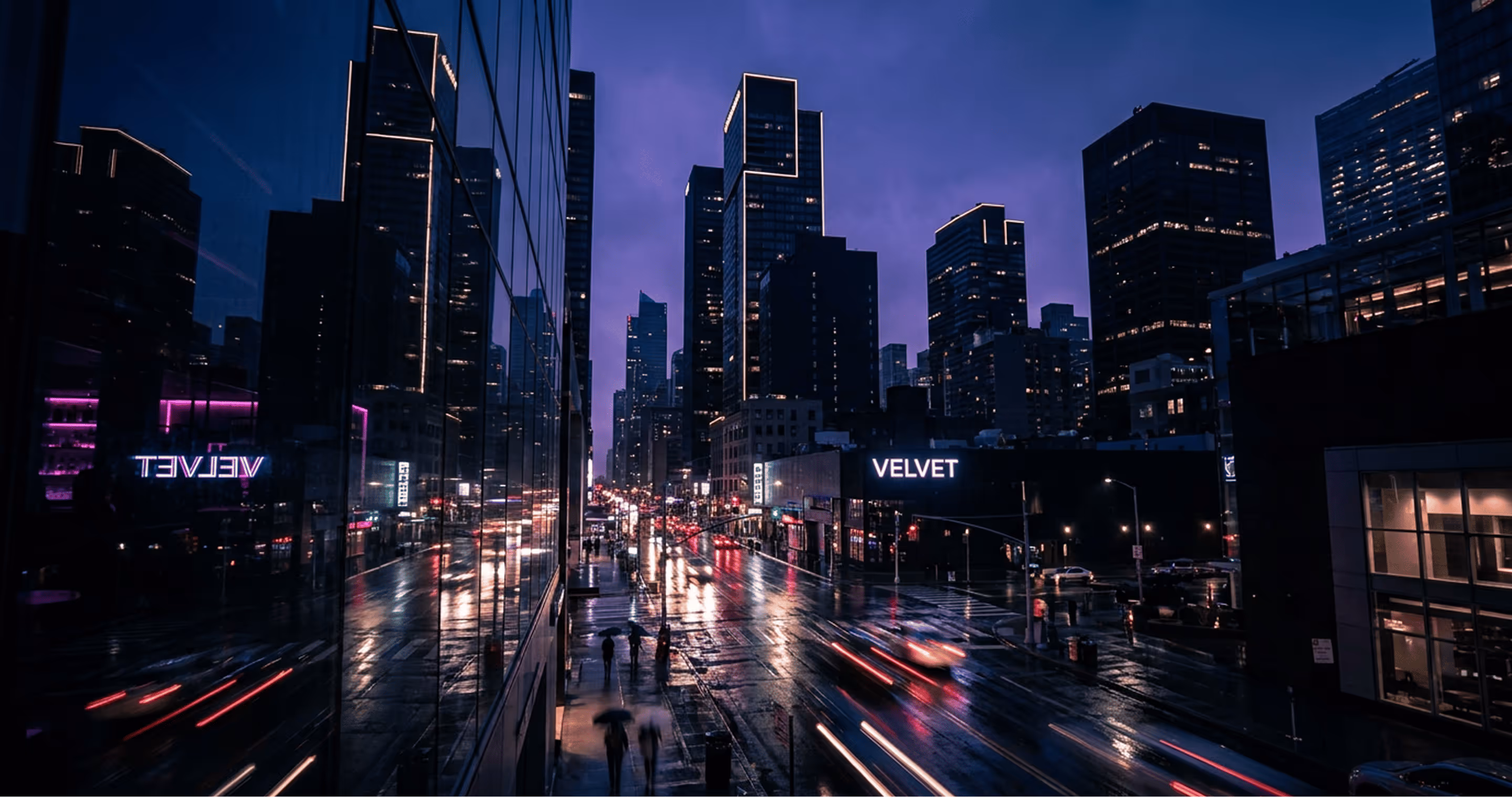 City street at night with wet pavement, blurred car lights, pedestrians with umbrellas, and tall illuminated buildings.