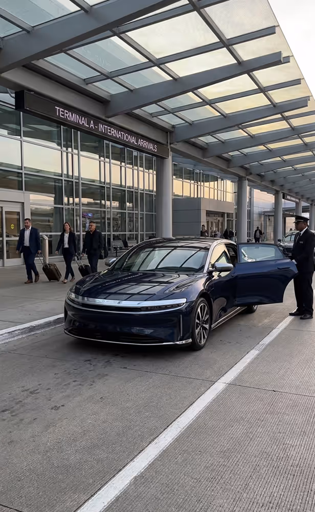 Black sedan with open passenger door parked outside Terminal A International Arrivals of an airport.