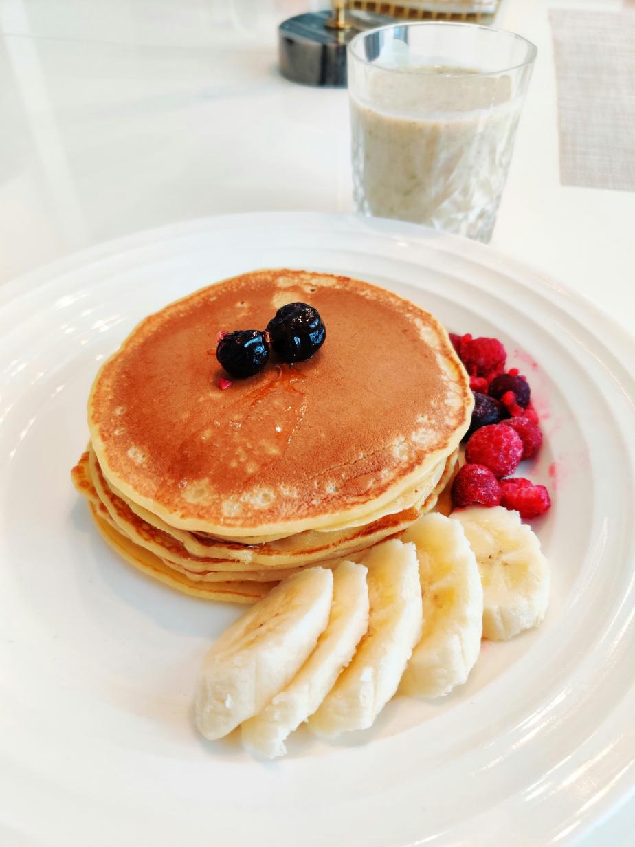 Stack of banana oat protein pancakes topped with Greek yogurt and blueberries on a plate
