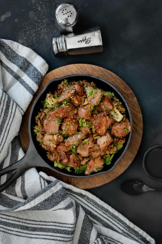 Chicken and tenderstem broccoli stir-fry with red pepper and noodles in a wok, topped with sesame seeds