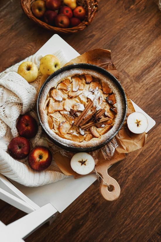 Baked oats with sliced apple and walnuts in a ceramic baking dish, dusted with cinnamon and served with Greek yogurt