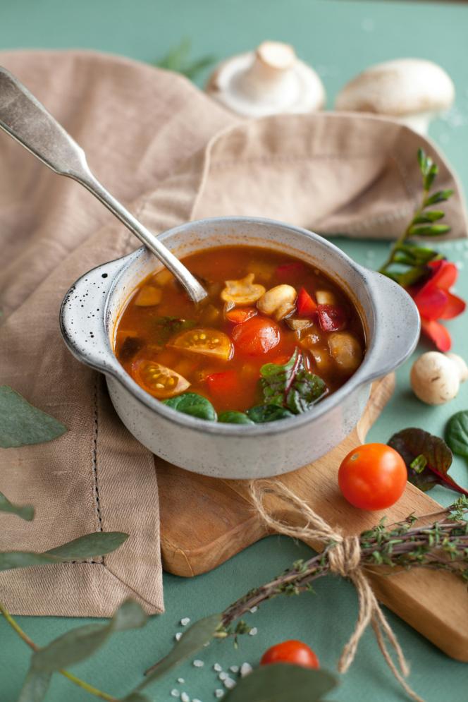 Bowl of minestrone soup with cannellini beans, small pasta, kale and vegetables, topped with grated Parmesan