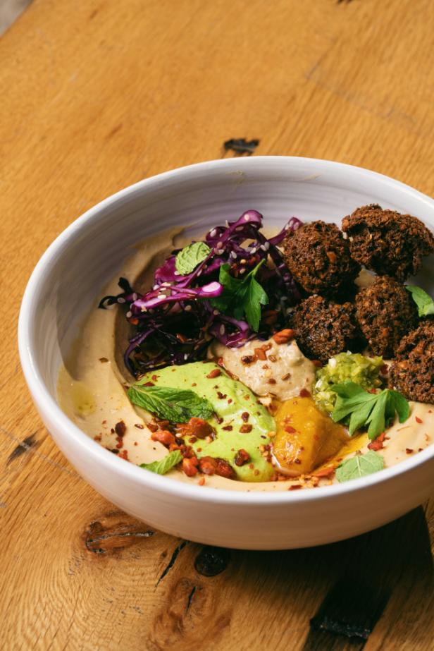 Bowl of baked falafel with quinoa tabbouleh, tomatoes, cucumber and a drizzle of tahini sauce