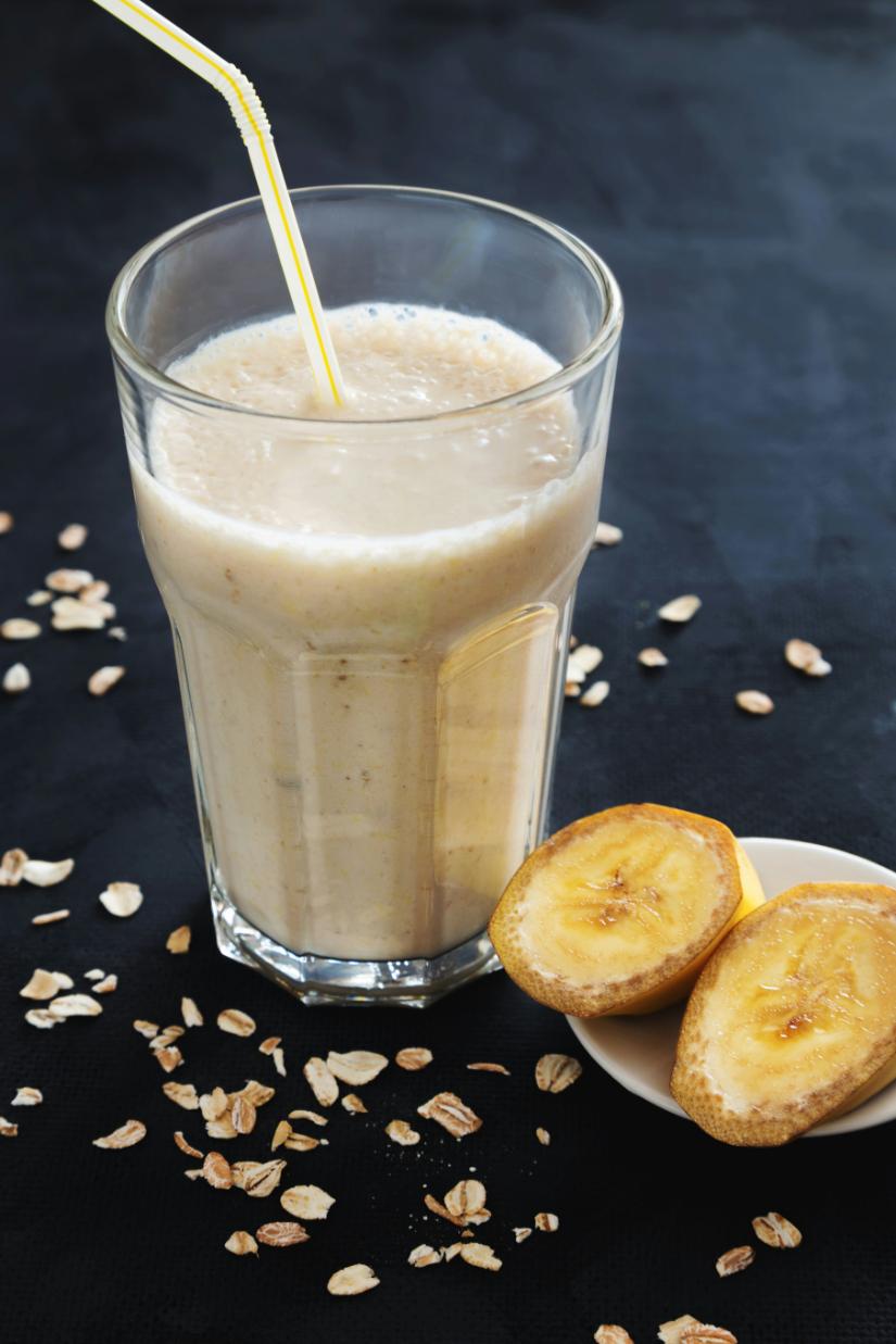Glass of banana, oat and peanut butter smoothie topped with oats and banana slices