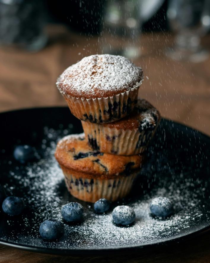 Healthy blueberry oat protein muffins on a board, with bursting blueberries and a golden top