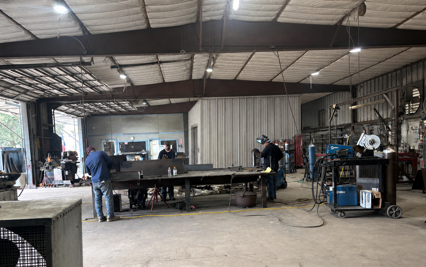 Skilled welder performing precision fabrication in a modern industrial manufacturing facility.