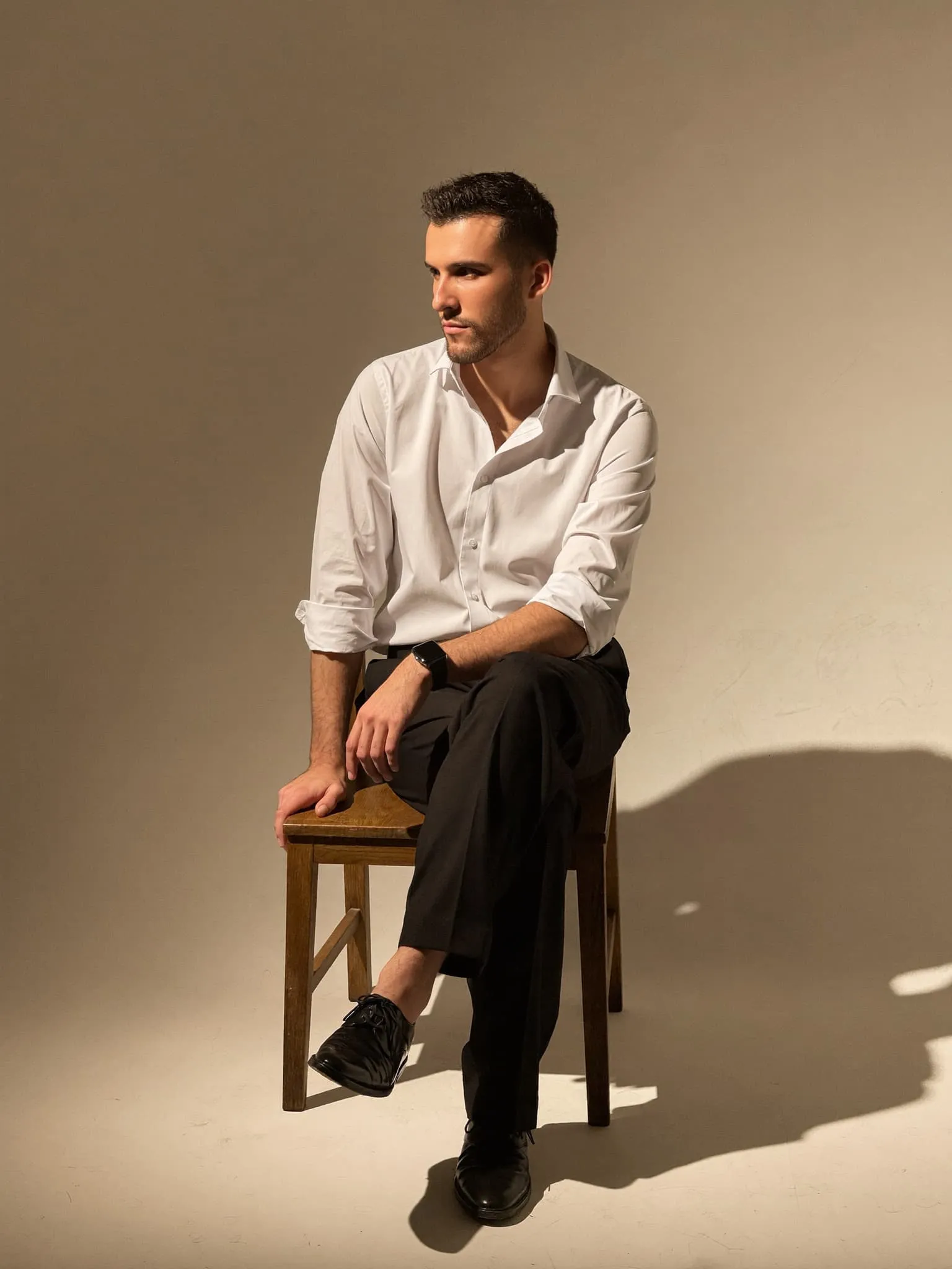 Man in a white shirt seated in a sunlit studio