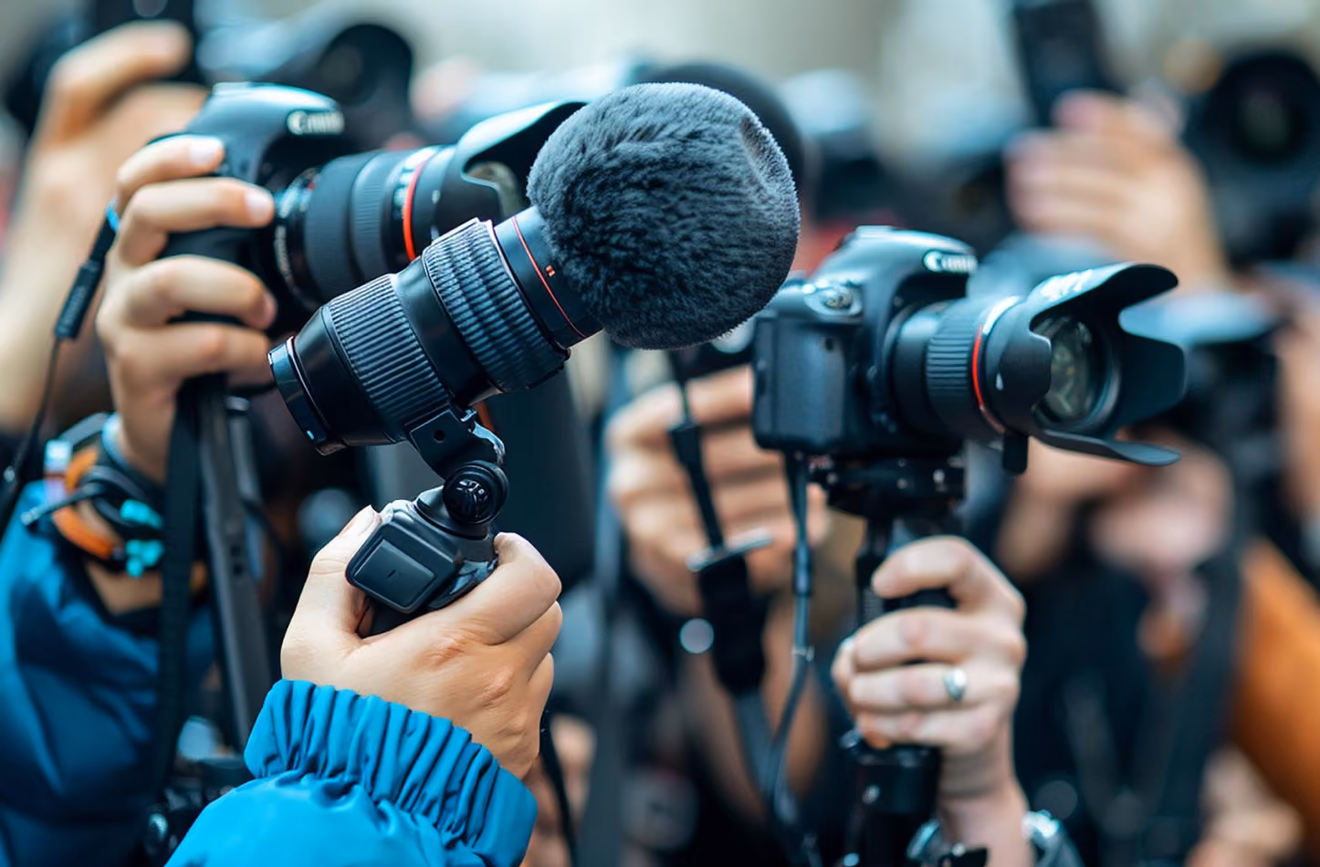 Journalists are holding microphones and cameras