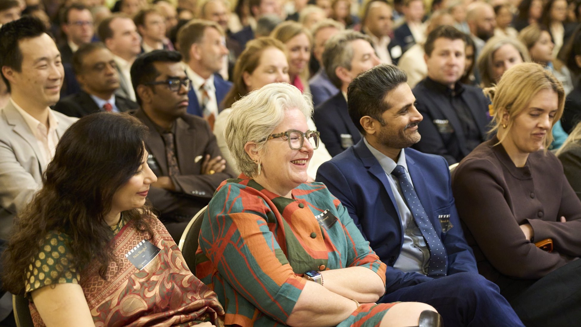 Guests in the front rows smiling and laughing during the speeches