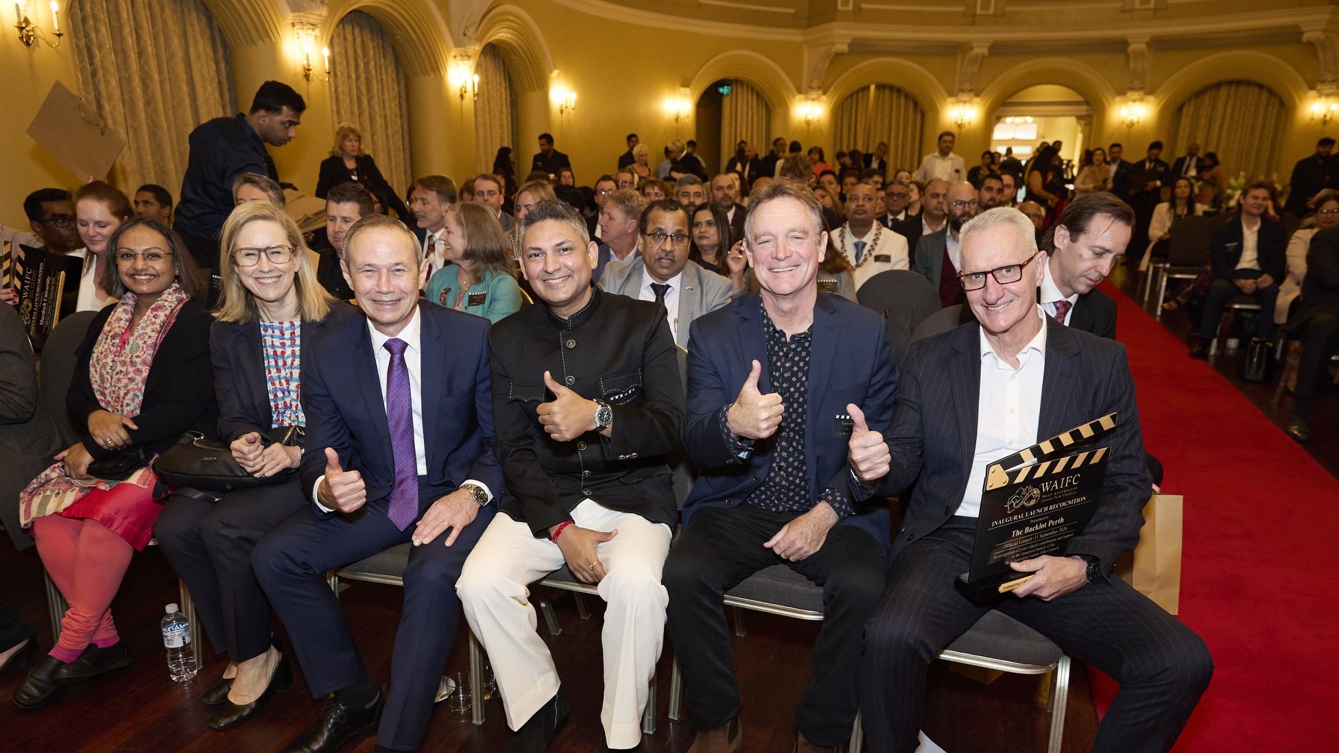 Guests seated in the front row giving thumbs up and holding a WAIFC clapperboard