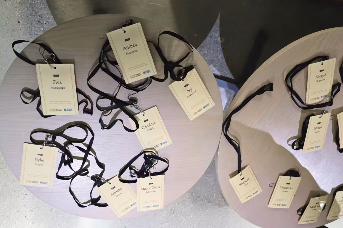 Name badges with black lanyards arranged on two round tables, each showing different names and titles.
