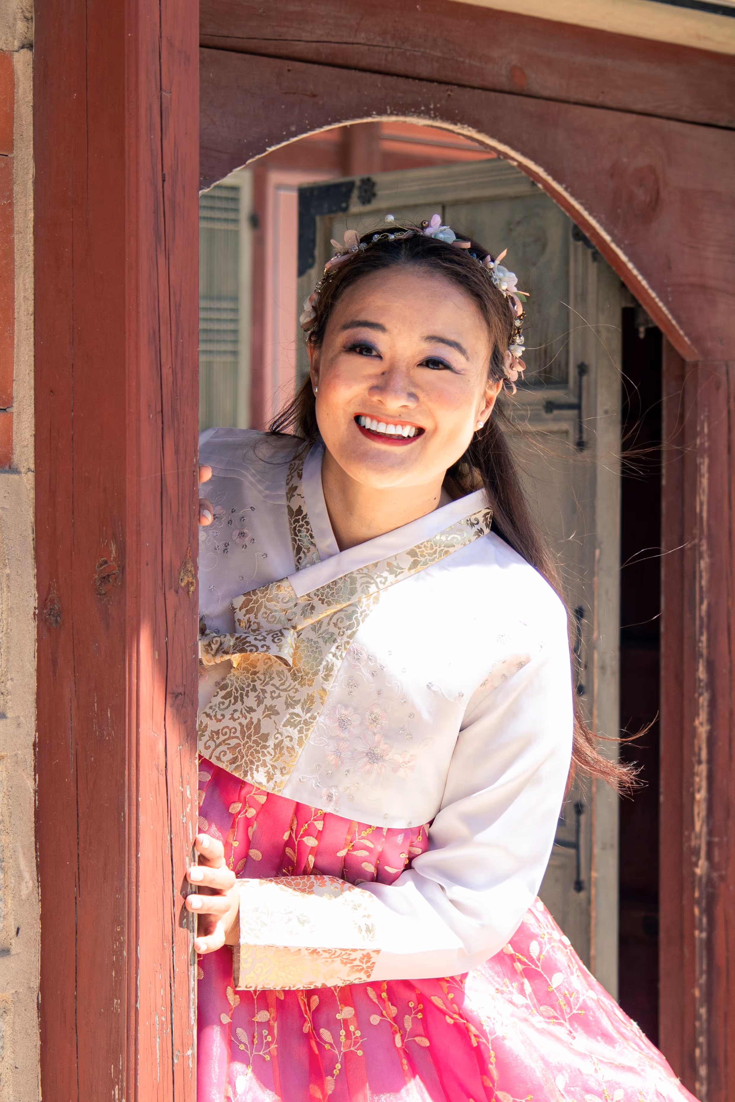 Mary Bowers wears a pink Hanbok, as she peeks around the corner at Gyeongbokgung Palace.