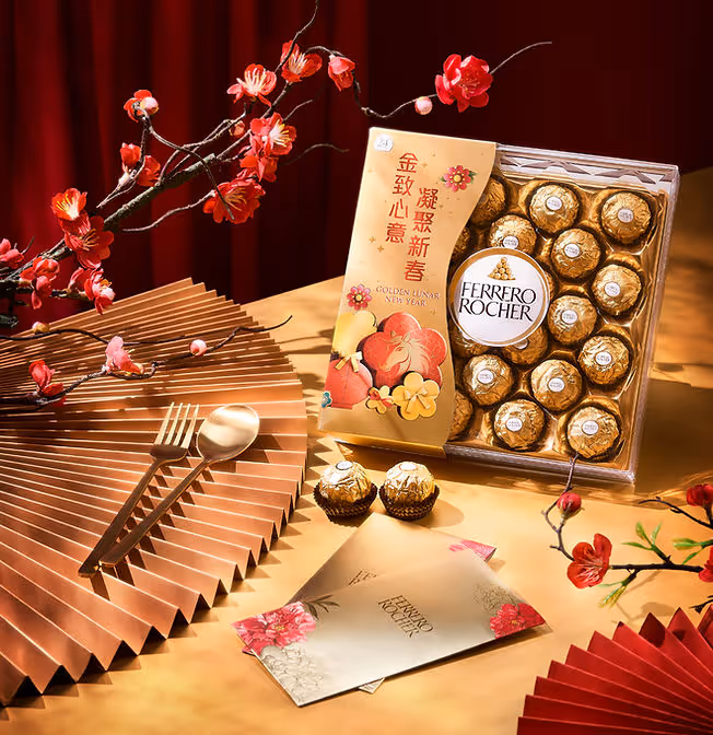 Ferrero Rocher chocolates in festive Lunar New Year packaging with red flowers and golden fork and spoon.